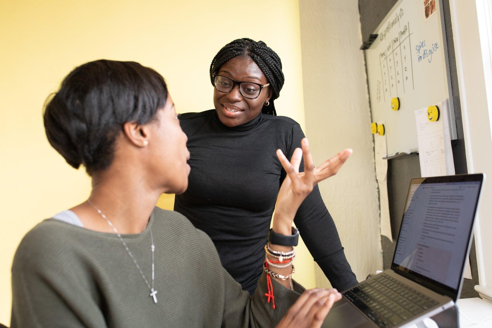 Woman speaking to her team member next to a computer and whiteboard.